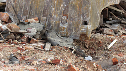 The iron bucket of the excavator removing the remains from the destroyed building
