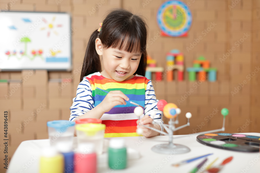 Wall mural young girl painting swivelling solar system toy at home