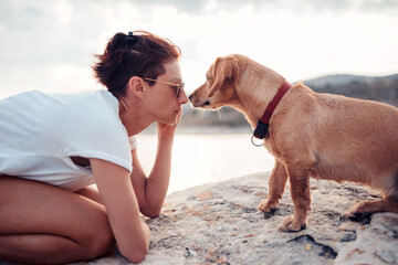 Woman trying to make eye contact with her dog on the beach
