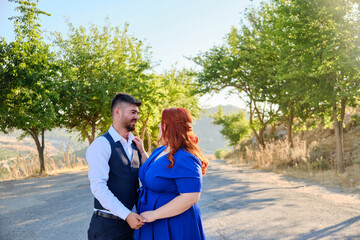 Caucasian plus size red headed woman and her turkish beloved man look to each other. Mixed race couple on a romantic date. Middle eastern man and caucasian woman marriage or engagement