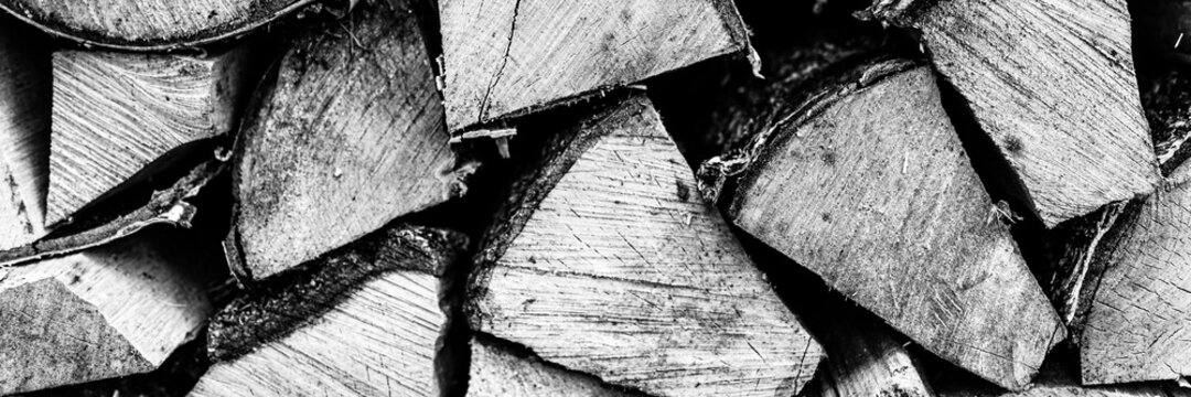 textured firewood background of chopped wood for kindling and heating the house. a woodpile with stacked firewood. the texture of the birch tree. toned in black white or gray color. banner