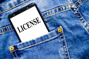 license the text is written on the white screen of the phone shortly lies in jeans. word