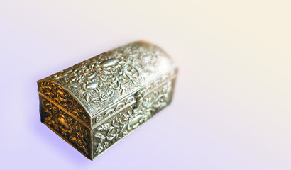 Silver shiny closed treasure chest or box isolated on a gradient light blue background. Selective focus, shallow depth of field