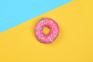 Naklejka na ściany i meble Donut with colored noodles, sweet. Two color background with overhead view.