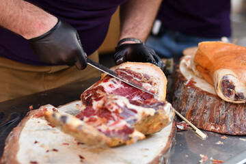 Butcher slicing meat with knife, rubber gloves on