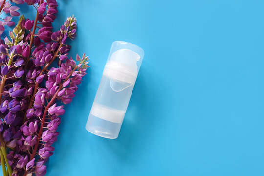 Unbranded transparent bottle of Intimate lubricant gel and purple lupine flower frame. Intimate massage and comfortable sex consept. Cosmetic bottle. Lifestyle, flatlay, top view, template.
