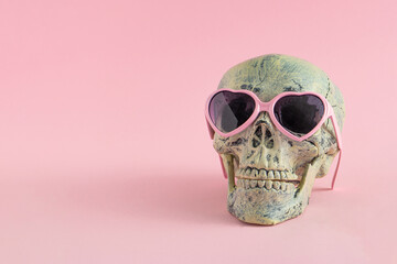Skull with glasses on pink background. Halloween creative fashion love concept. Copy space.