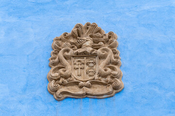 Masonry coat of arms on a blue wall.