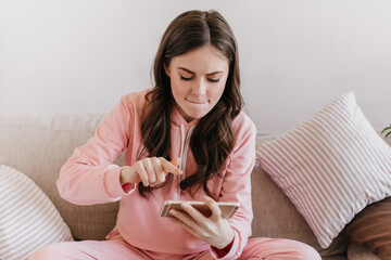Girl in pink suit with zeal presses screen of phone while playing game. Shot of woman in sport...
