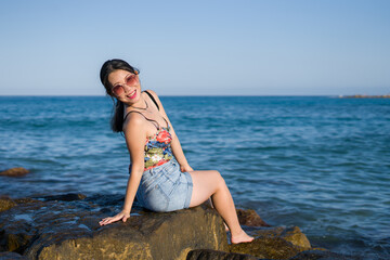Fototapeta na wymiar young Asian woman by blue sea - happy and beautiful Chinese girl enjoying holiday trip relaxed and cheerful at beach rock cliff during summer in tourist travel concept