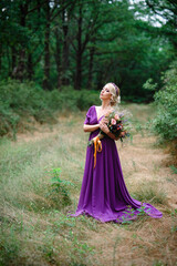 Fototapeta premium Girl model blonde in a lilac dress with a bouquet