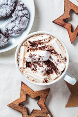 Christmas or New Year festive background. Hot chocolate or cocoa with marshmallows in white cup, christmas decorations, top view, white fabric background.