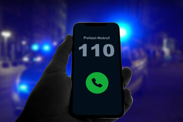 Person hält Smartphone in der Hand und ruft den Notruf 110 der Polizei, im Hintergrund des...