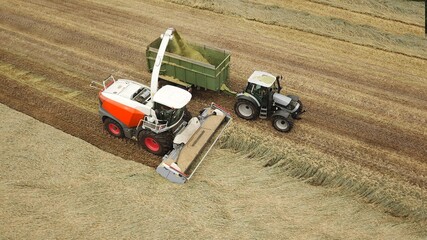 Erntearbeiten aus der Vogelperspektive: Feldhäcksler und Traktor mit Anhänger bei der Ernte auf...