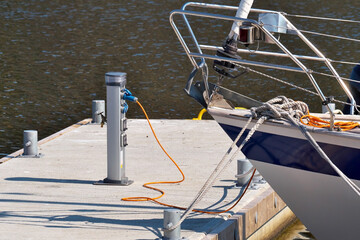 The yacht in the port at the pier is connected to electricity.