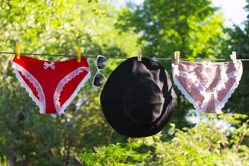 Women's underwear is drying on a rope. Hanging panama hat and sunglasses