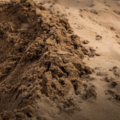 Wet sand sitting on top of dry sand, during a sunny day at the beach