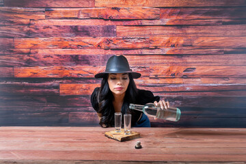 Beautiful and sensual Latin woman wearing fedora hat and serving shots of tequila