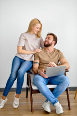 caucasian couple have online communication with friends on relatives, use laptop, smiling, enjoying weekends at home together, side view portrait. In bright cozy room. Relax, leisure, rest, family