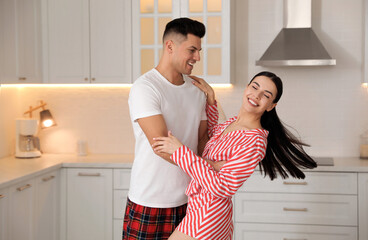 Happy couple wearing pyjamas and dancing in kitchen