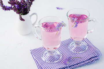 Fresh water with lavender in glasses and a bouquet of flowers in a jug on the table. Lavender aromatic cocktail. Copy space
