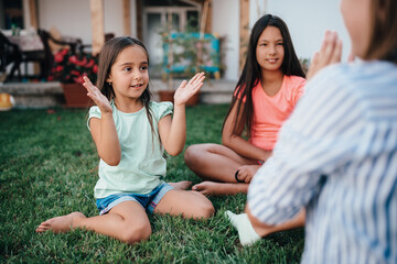 Girls sitting on the grass and playing hand-clapping games