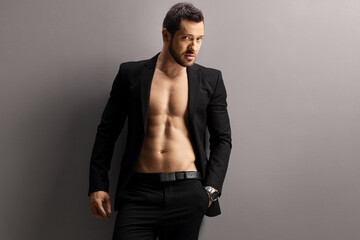 Male model in a black suit posing shirtless and looking at the camera