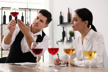 Sommeliers tasting different sorts of wine at table indoors