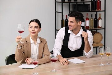 Sommeliers tasting different sorts of wine at table indoors