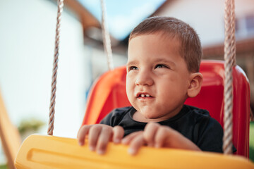 Toddler boy sitting on the swing at backyard