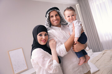 Happy Muslim family with little son in bedroom