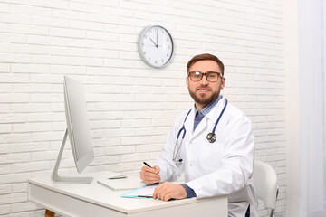 Portrait of pediatrician at table in clinic