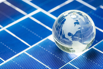 Glass globe on blue photovoltaic solar cells. Globe and Americas. Electric solar battery panels. Concept of an environmentally friendly method of converting solar energy into electricity. Free space.