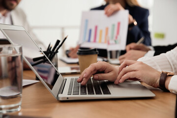 Woman using laptop at table in office during business meeting, closeup. Management consulting