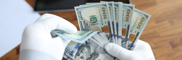 Man in white gloves counting american dollars closeup