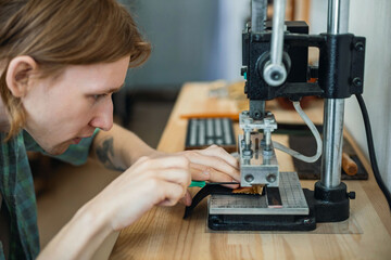 Male tanner stamping stuff use awl and machine device working at leather workshop. Handmade work