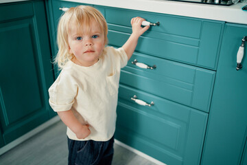 Good children's mood weekend holidays. Playing at home stands alone on the kitchen floor. The child is blond and has a European appearance. Country house in the village in summer.