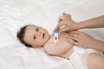Obraz na płótnie Canvas Mother measuring her baby's temperature, closeup. Health care