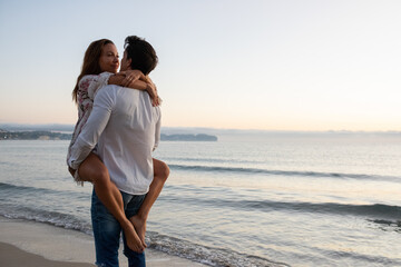 Fototapeta premium Man carrying woman near waving sea