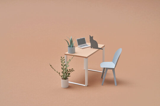 Papercraft cat sitting near laptop on table