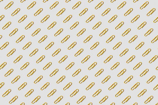 Pattern of yellow paper clips on gray background