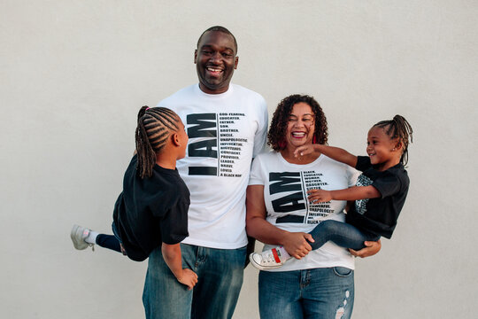Laughing Black parents carrying daughters 