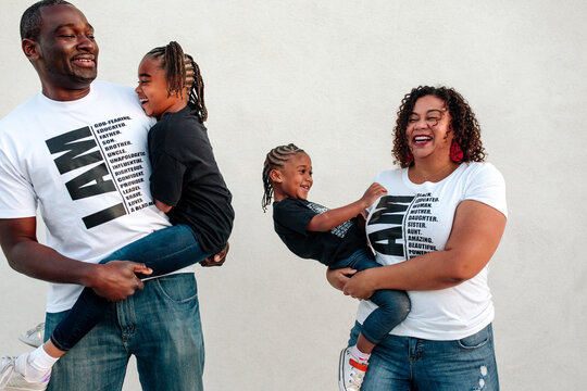 Happy Black parents carrying daughters