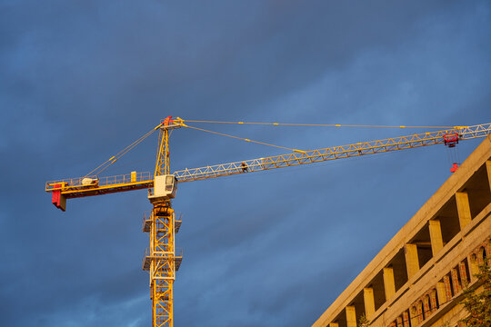 Tower crane against the cloudy sky in sunlight.