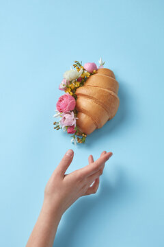 Woman reaching croissant with flowers