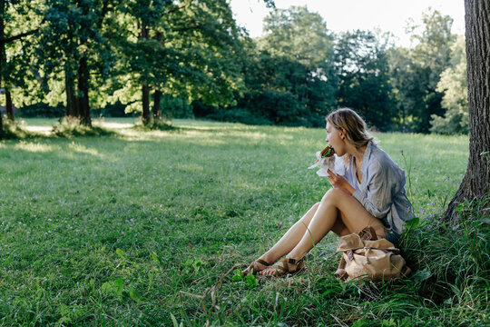 Female eating sandwich while sitting under tree during short local trip