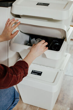 Housewife throwing tin into trash bin for recycling