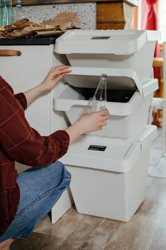 Housewife throwing glass bottle into trash bin for recycling