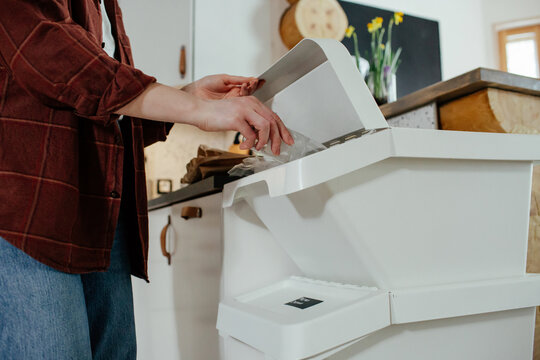 Housewife throwing plastic bottle into trash bin for recycling