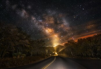 This image shows an epic night time milky way sky over a remote, secluded road